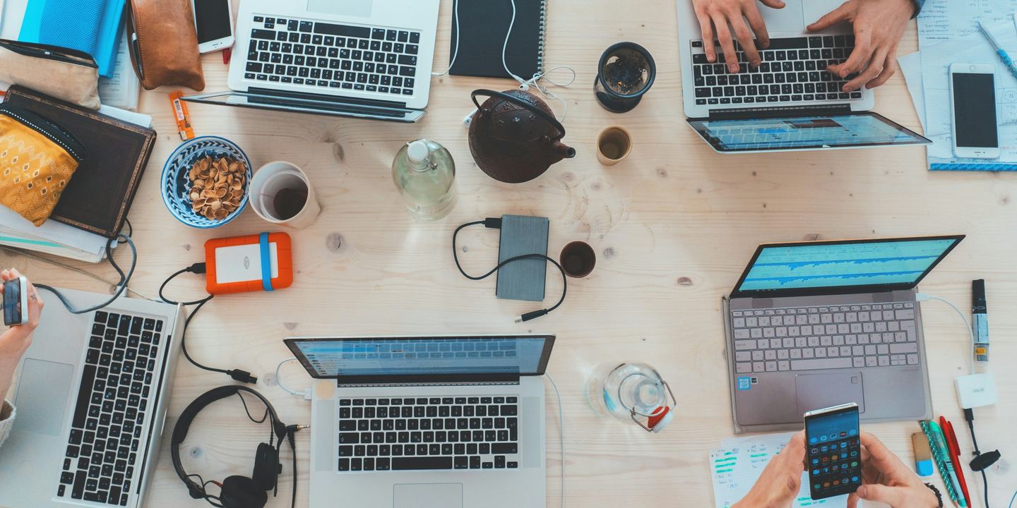 Overhead view of people collaborating around a table with laptops and notebooks.